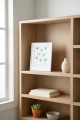 Small matted blue flower botanical artwork leaning on a light airy bookshelf