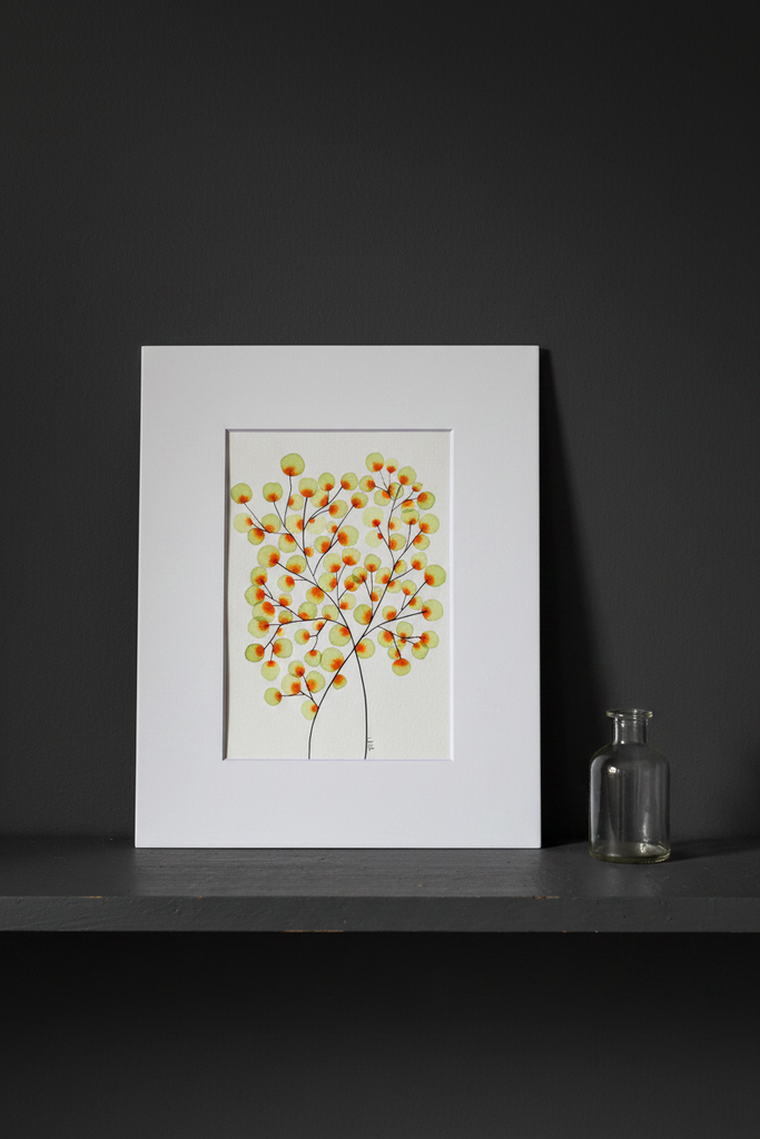 Green and orange tree botanical artwork on a dark moody shelf